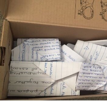 A cardboard box full of folded up notes.
