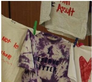 The image of several tees on a clothesline. The tees bear messages from assault survivors.
